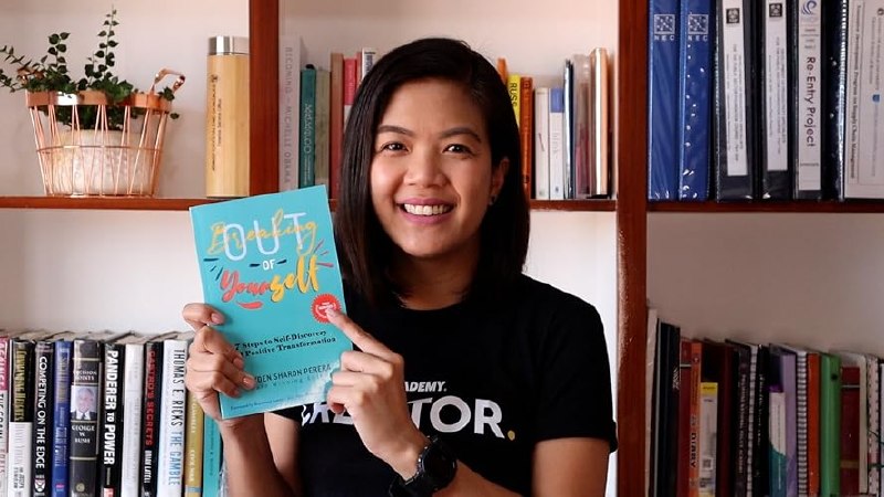 Reader holding Breaking Out of Yourself in front of bookshelves